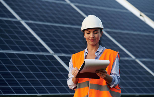 istock Notepad in hands. Female worker engineer in uniform is near solar panels 2179152875