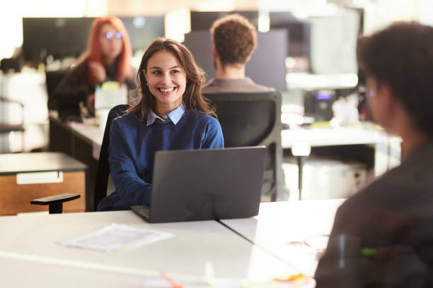 istock Happy female programmer using laptop and talking to her colleague. 2179157296
