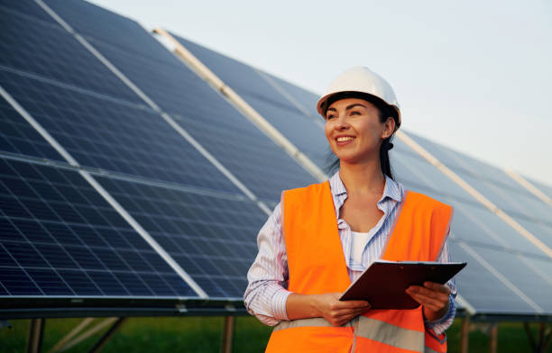 istock Black notepad in hands. Female worker engineer in uniform is near solar panels 2179160038