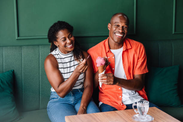 istock Happy couple sharing a laugh with ice cream at a cafe 2179161642