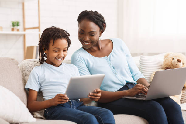 istock Afro mom and daughter doing school homework on sofa 2179161801