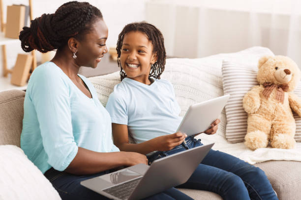 istock Black mom and daughter browsing Internet on sofa 2179161812