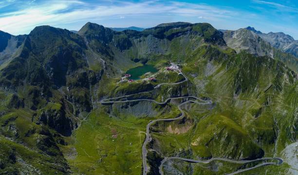 The Transfagarasan Highway winding through the Fagaras Mountains with Lake Balea in the background An aerial view of the Transfagarasan Highway winding through the Fagaras Mountains with Lake Balea in the background, on a sunny day in Romania balea lake romania stock pictures, royalty-free photos & images