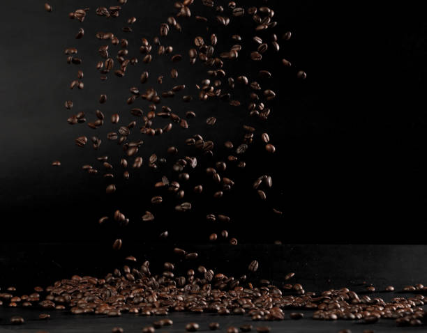 istock Coffee beans flying splashing in mid air. Black background isolated element. Many Coffee Beans flying explosion in air with aroma scent 2179164038