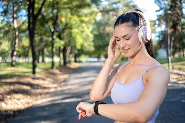 istock Smiling young girl with headphones checking her smart watch, tracking progress while exercising outdoors. 2179164280