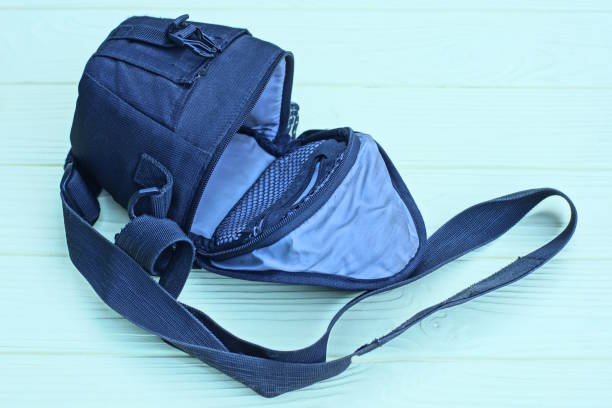 one open black gray bag made from cloth lies on a yellow wooden table