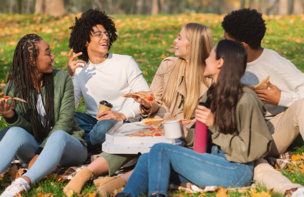 istock Cheerful closed friends having fun at park, eating pizza 2179167272