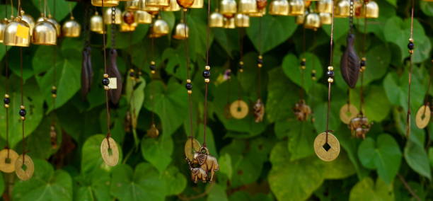 istock Hanging Golden Wind Chimes Close-Up Green Leafy Background 2179167602