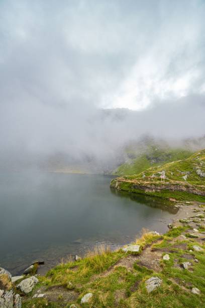 istock Serene mountain lake with misty clouds. 2179169112