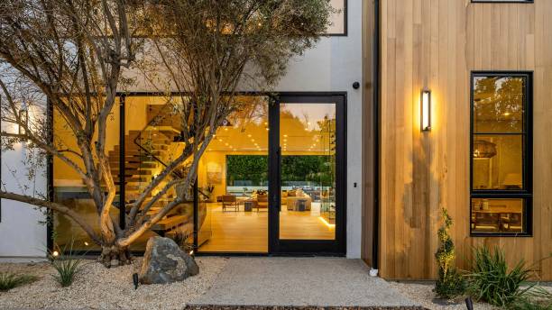 Modern home exterior with glass doors and warm lighting.