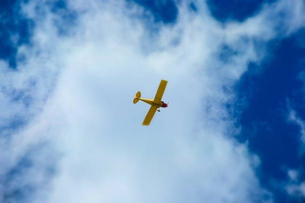 A yellow toy airplane is in flying mode in the sky.