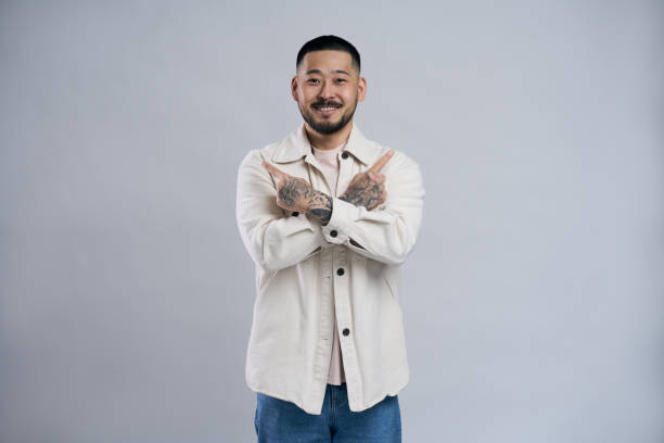 istock Smiling asian man pointing two index fingers sideways 2179185823
