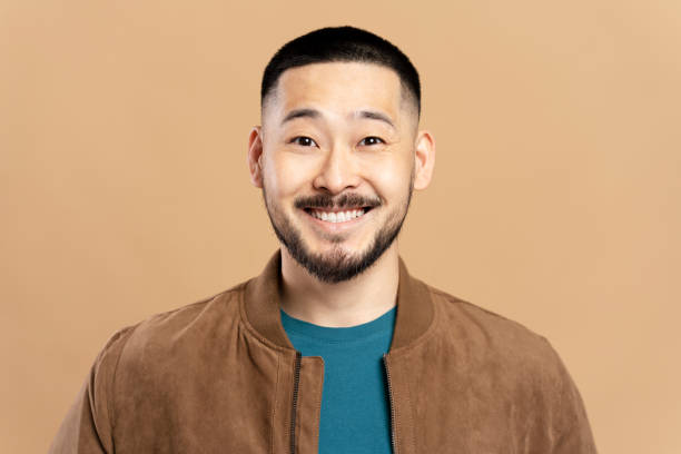 istock Young man smiling wearing brown jacket on beige background 2179185948