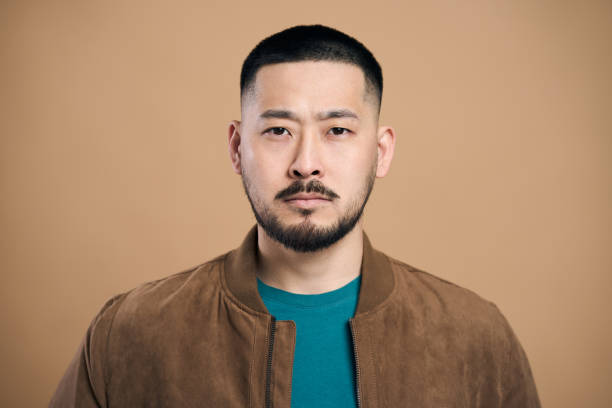 istock Serious young asian man posing on beige background 2179185984