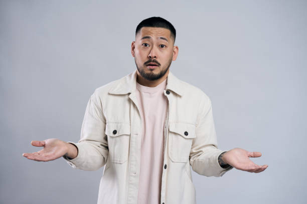 istock Confused asian man shrugging with open palms posing in studio 2179186021