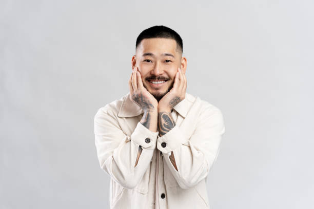 istock Young man with tattoos smiling and holding his face 2179186040