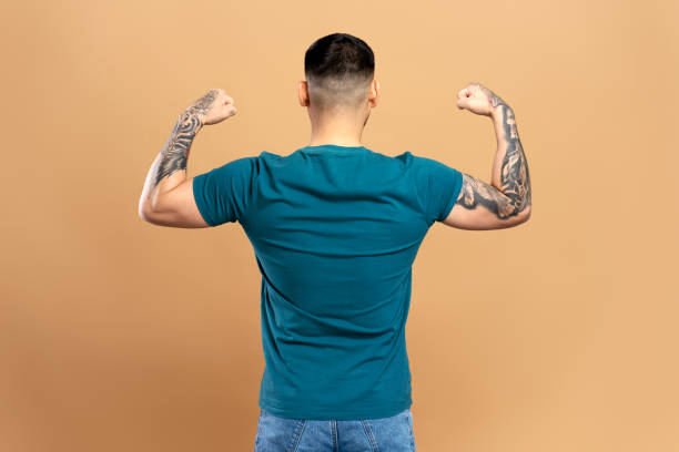 istock Man with tattooed arms showing muscles from behind 2179186430