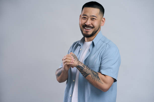 Happy smiling handsome man with tattoos is rubbing his hands