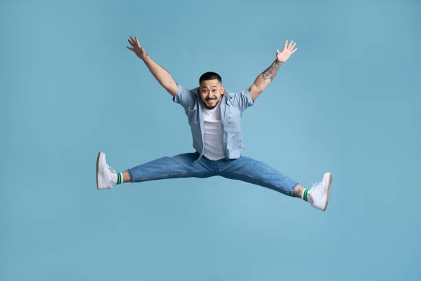 istock Carefree young man is jumping with raised arms and legs spread 2179187492