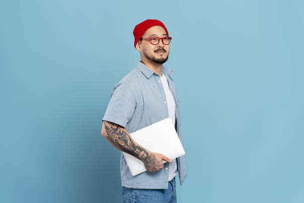 istock Asian man holding laptop in hand on blue background 2179188063