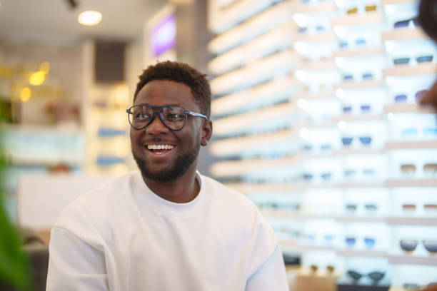 Young man is trying on prescription eyeglass frames at the optician's.
