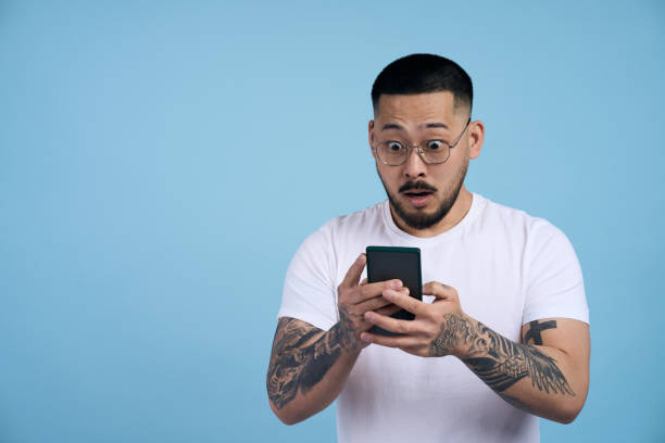 istock Shocked man reacting to phone content on blue background 2179192344