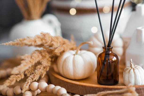 Aroma diffuser. Autumn scented perfumes for the home in a glass bottle with sticks as an air freshener in the house and pumpkins. Aromatherapy, cozy atmosphere, comfort and relaxation.