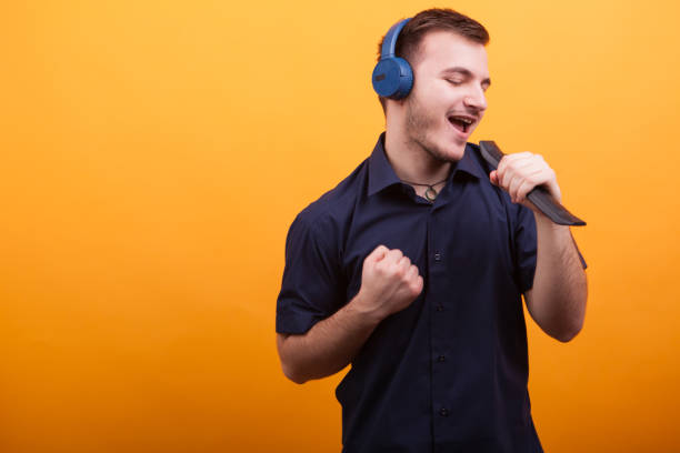 istock Young man singing amd feeling good while having headphones over yellow background 2179204924