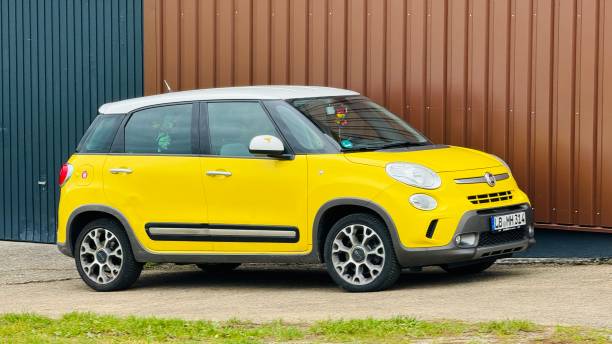Erdmannhausen, Germany - 10/14/2024, Yellow small Fiat car parked at a brown wall