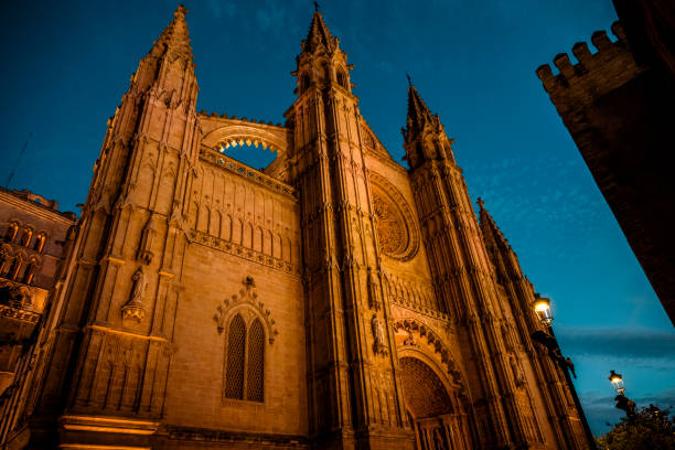 The La Seu Cathedral in Palma de Mallorca glows in golden hues against the twilight sky, showcasing its magnificent Gothic architecture and towering spires, a testament to centuries of craftsmanship and faith.