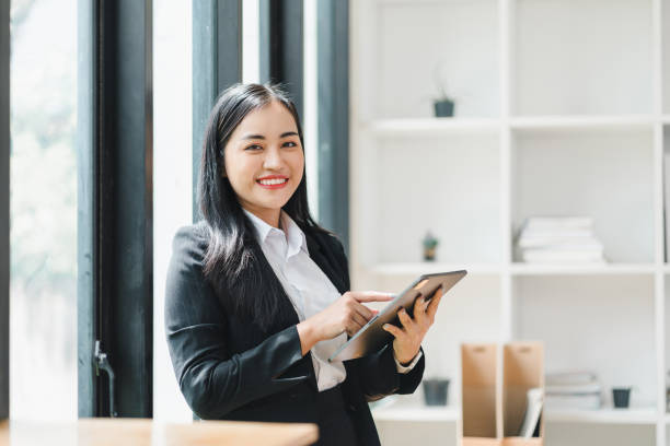istock confident woman in business suit smiles while using tablet in modern office setting, showcasing professionalism and engagement. 2179219471