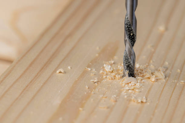 istock metal drill bit and pine wood board during operation 2179219930