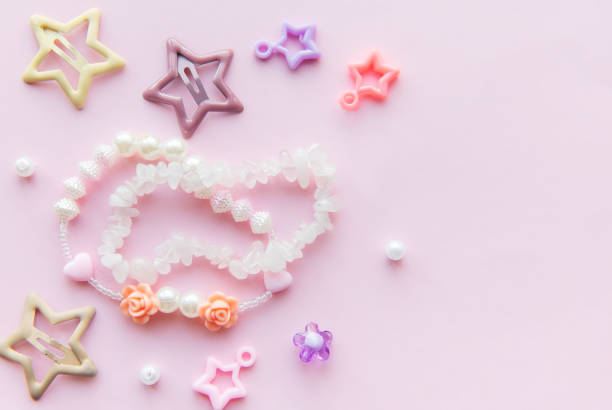 A variety of colorful beads, including stars and flowers, are spread out against a soft pink background, showcasing creativity in crafting and jewelry making.
