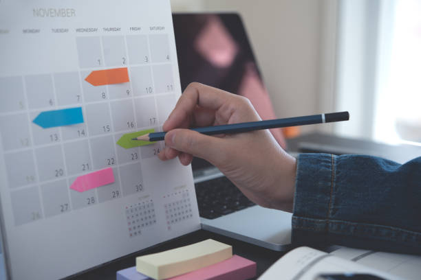 istock 2025 Event planner timetable agenda plan on schedule event. Business woman checking planner, taking note on calendar desk with laptop computer on office table. Calendar event plan, work planning 2179222067