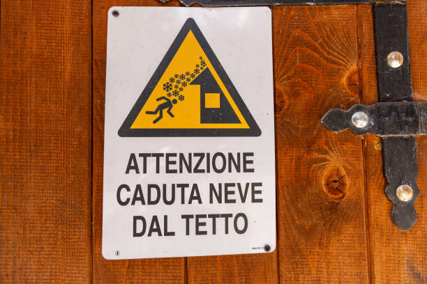Close-up of a yellow triangular warning sign with text in Italian, \
