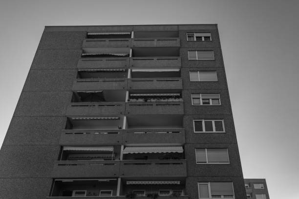 istock A tall, grey apartment building with many balconies stands against a bright sky 2179225550