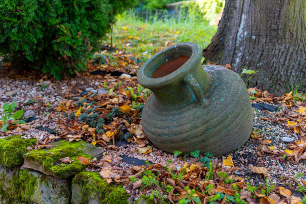 A textured clay vase decorates a vibrant forest scene during spring and early summer.
