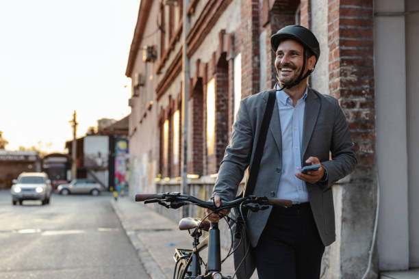 istock Smiling businessman wearing helmet and holding smartphone while commuting on a bicycle 2179226804