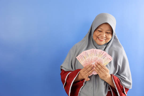 istock Middle Age Woman Smiling Happy Face While Holding Money, On Blue Background 2179227619
