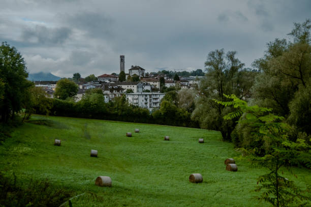 Cityscape view of Castion, province of Belluno with the Bell tower of the curch ar the center of the photo with the field full of balers harvested.