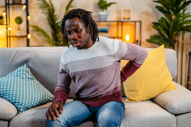 istock Young Man Having Back Pain While Sitting On The Sofa At Home At Night 2179228529