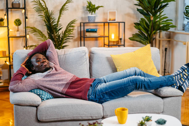 Young Man Relaxing On The Sofa At Home At Night