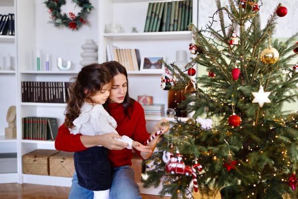 istock Caring mother decorating a Christmas tree with her little girl 2179233876