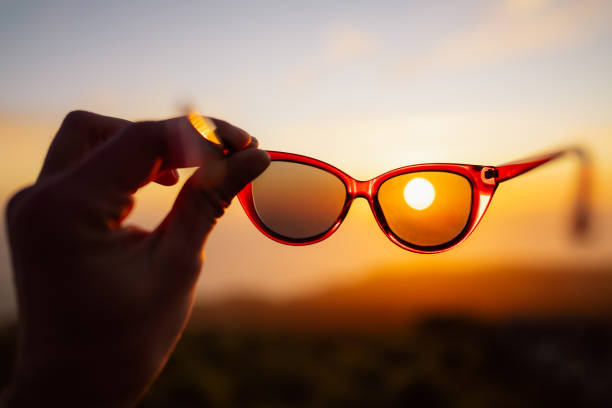 istock Hand Holding Sunglasses Framing a Scenic Sunset View 2179238947