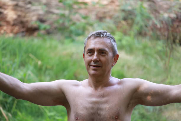 Young man breathing fresh air in a green forest, enjoying the nature and relaxing