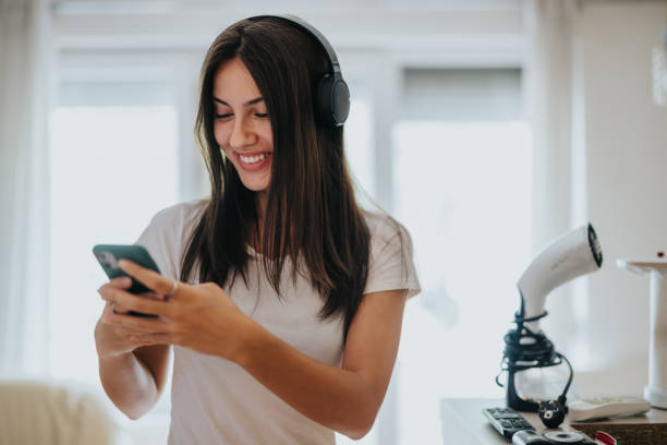 Young woman enjoying music on headphones while using smartphone