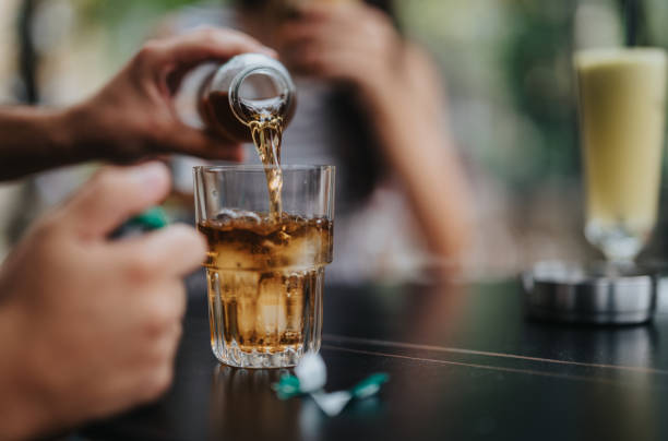 istock Close-up of hands pouring refreshing beverage into glass on table 2179248025