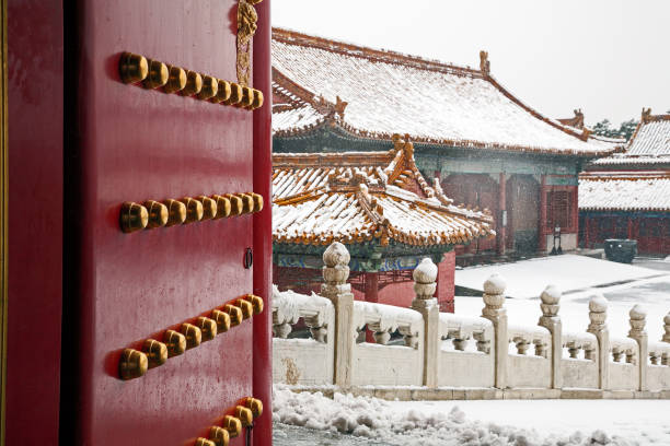 A doorway and building in the Forbidden City after a late season snow storm. The nine rows of nine knobs on the door, represents longevity and the supreme power of the emperor. , Beijing, China