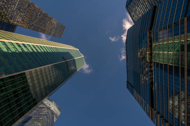 Angled view of modern skyscrapers in business district against blue sky. Looking Up high-rise office buildings. Evening time, sunset. Orange, yellow and gold shades of color.