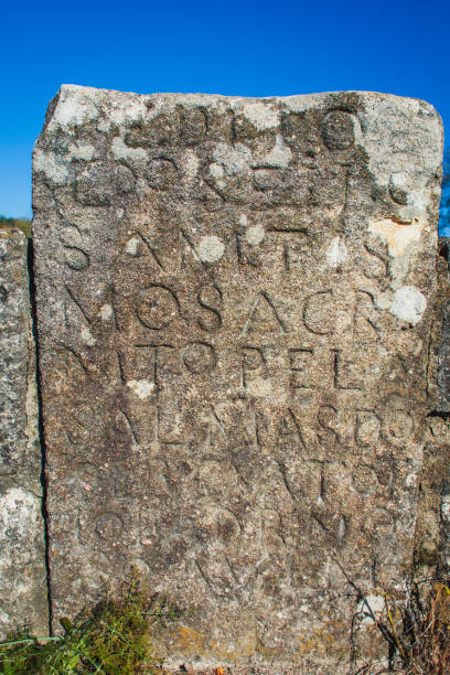 istock a weathered stone with ancient inscriptions, possibly a memorial or informational marker from a historical period. The stone's surface is rough and shows signs of erosion, with some parts of the carved letters less visible 2179310156